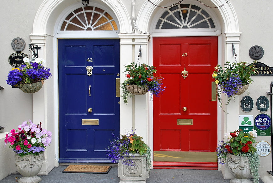 Vibrant Blue And Red Front Doors With Flower Baskets In Ireland