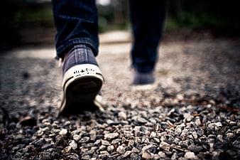 Low angle view of sneakers walking on gravel path