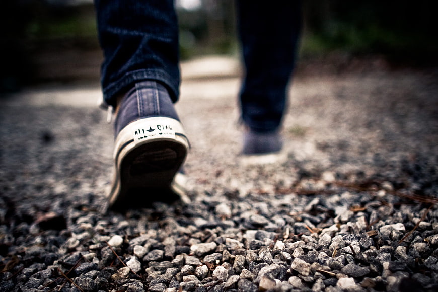 Low angle view of sneakers walking on gravel path