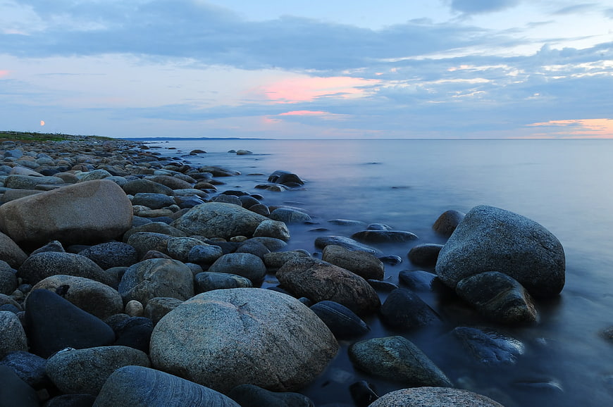 Serene Rocky Beach at Sunset with Smooth Water