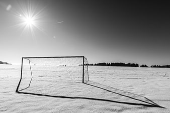 Black and white soccer goal on a snowy field under a bright sun