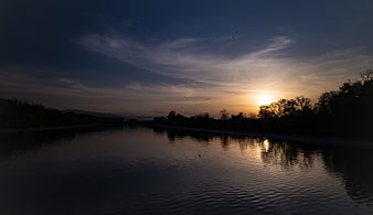 Serene Sunset Reflection on Calm River with Silhouetted Trees