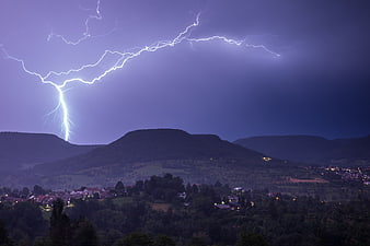 Dramatic Lightning Strike Over Mountainous Landscape at Night