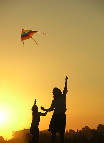 Silhouette of Mother and Child Flying Kite at Sunset