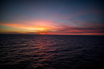 Vibrant Sunset Over Dark Ocean Horizon