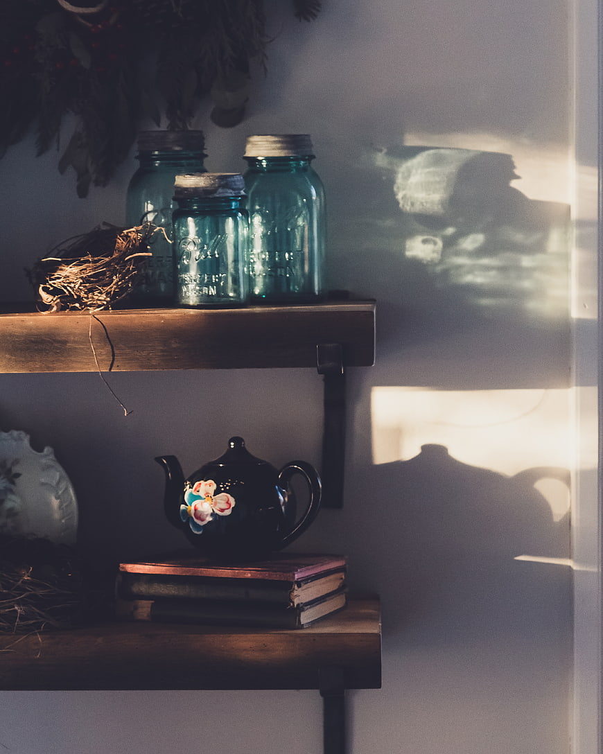 Rustic wooden shelves with vintage jars and teapot in sunlight