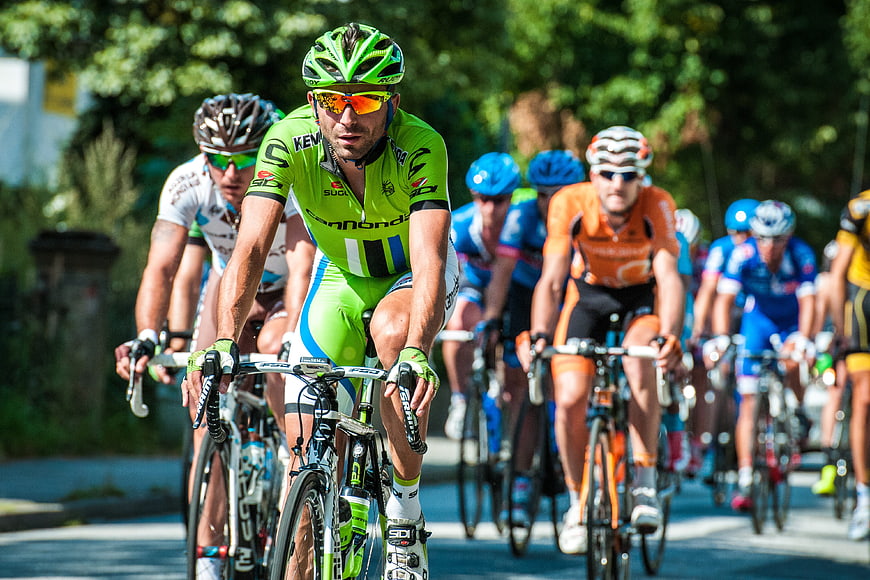 Professional Cyclists Racing on Road in Bright Sunlight