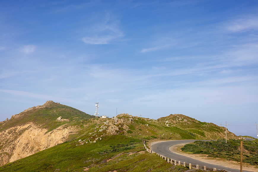 Winding Mountain Road with Cell Tower and Blue Sky