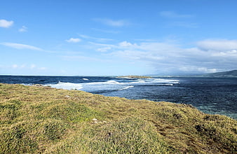 Grassy Coastal Cliff Overlooking Blue Ocean and Waves