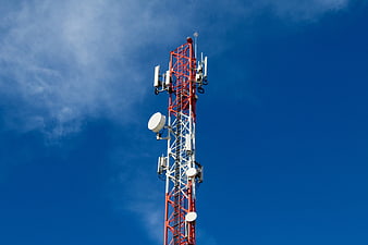 Red and white telecommunications tower against blue sky