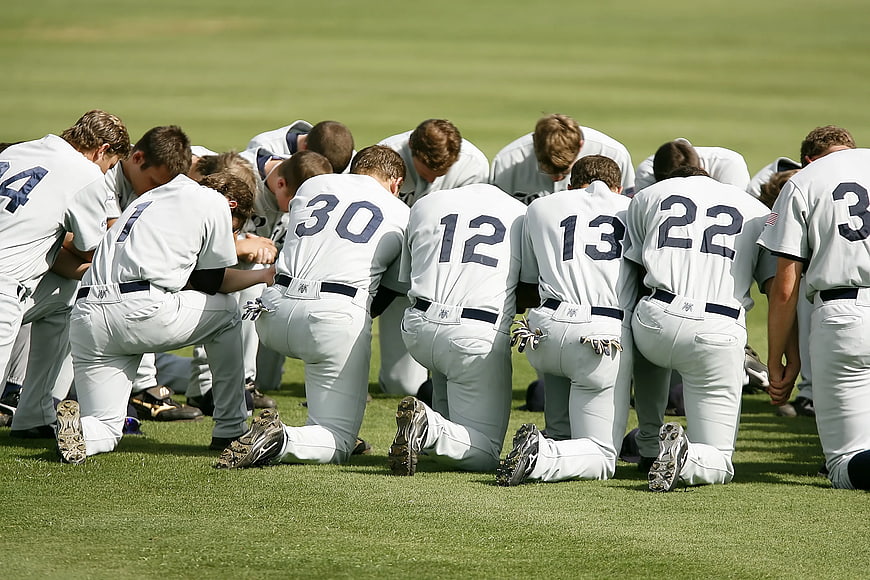 Baseball Team Kneeling in Prayer on Grass Field