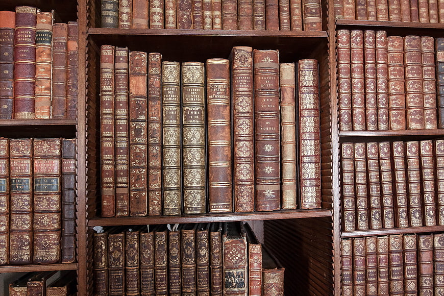 Antique leather-bound books on wooden shelves in a historic library