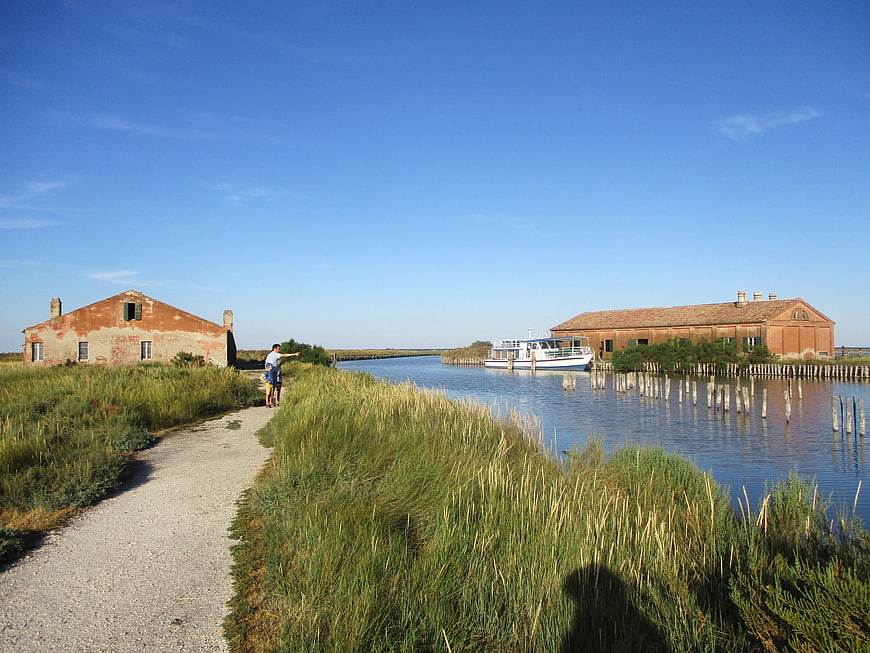 Couple walking along canal path near historic Venetian lagoon buildings