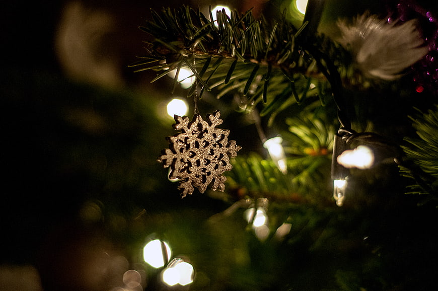 Close-up of silver snowflake ornament on Christmas tree with lights