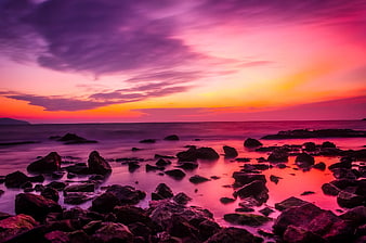 Vibrant Pink and Purple Sunset Over Rocky Coastal Shoreline