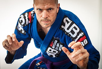 Intense male BJJ fighter in blue gi with purple belt