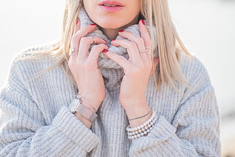 Close-up of Woman in Grey Sweater with Jewelry and Red Nails