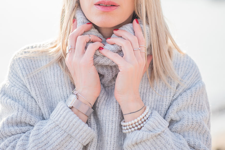 Close-up of Woman in Grey Sweater with Jewelry and Red Nails
