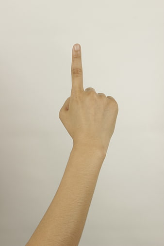 Hand pointing upward with index finger against a plain white background