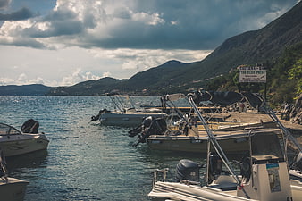 Motorboats docked at a scenic coastal bay with mountains