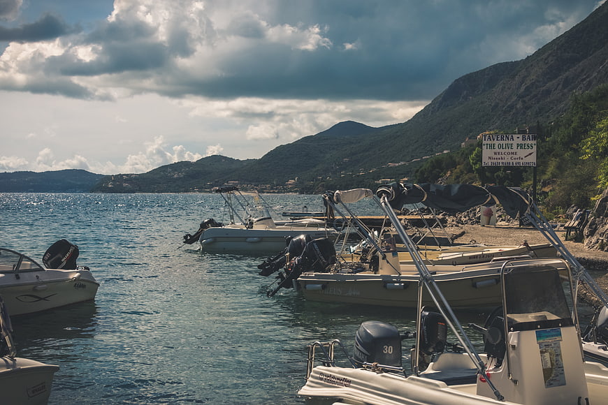 Motorboats docked at a scenic coastal bay with mountains