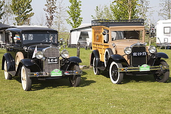Two vintage classic cars parked on grass at outdoor show