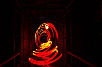 Abstract red light painting spiral in dark industrial tunnel