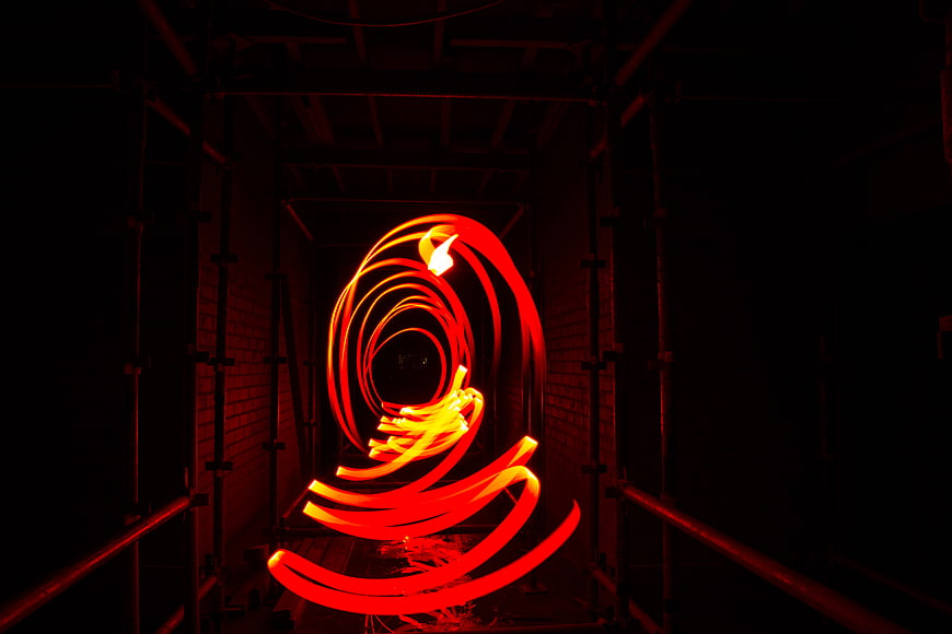 Abstract red light painting spiral in dark industrial tunnel