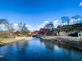 Scenic River View with Red Brick Buildings and Blue Sky