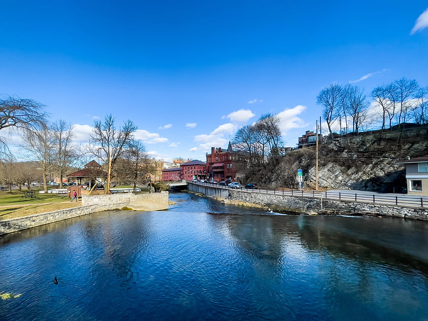 Scenic River View with Red Brick Buildings and Blue Sky