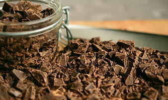 Close-up of chopped dark chocolate pieces in a glass jar