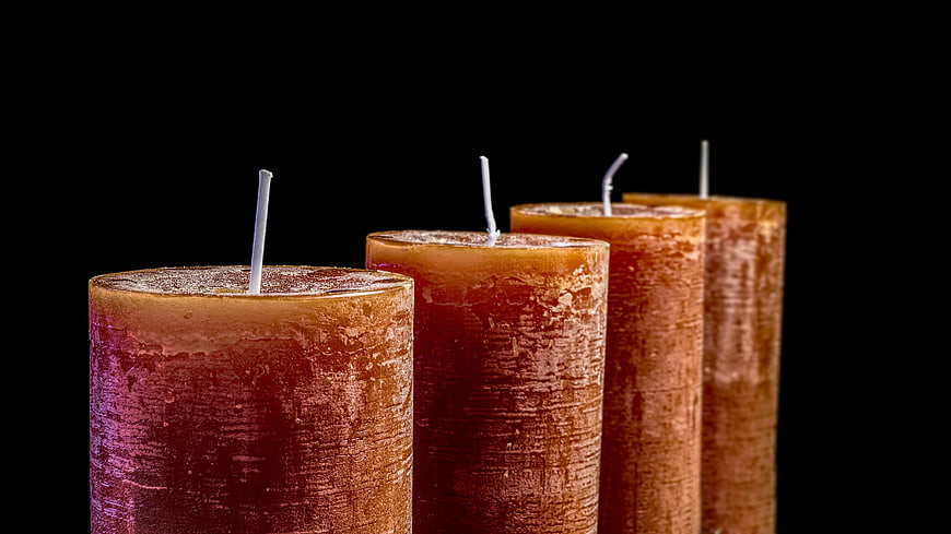 Four textured amber candles on black background