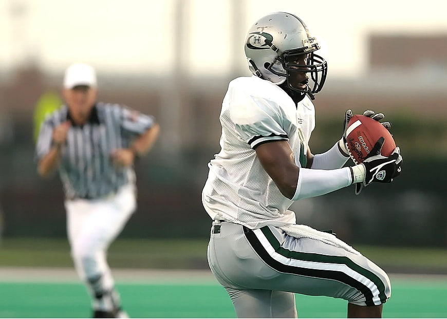 American Football Player Catching Ball on Green Field