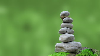 Stacked Zen Stones on Mossy Rock with Green Background