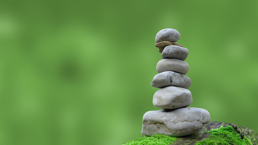 Stacked Zen Stones on Mossy Rock with Green Background