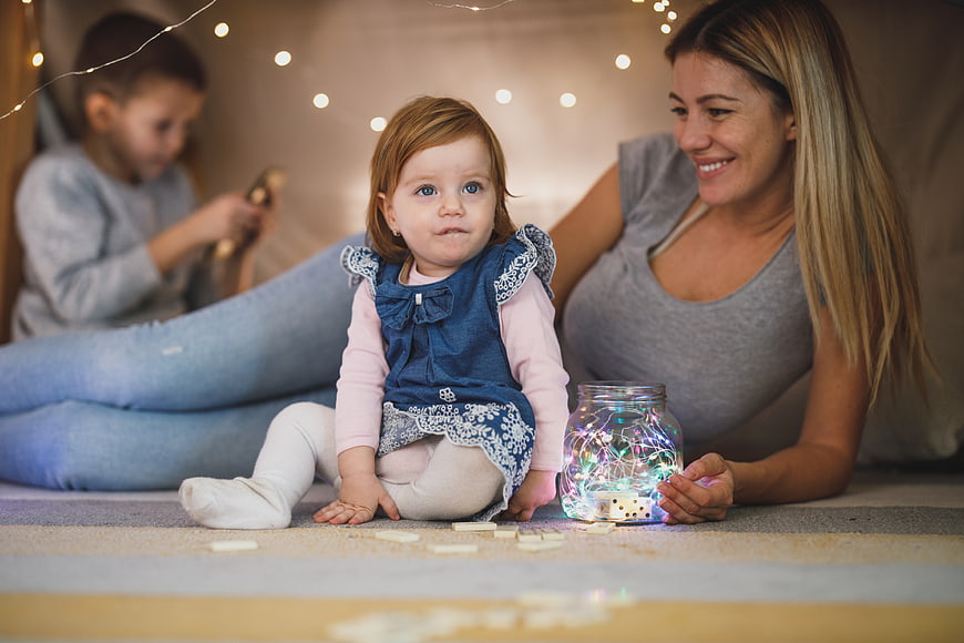 Mother and Toddler Playing with Fairy Lights Indoors