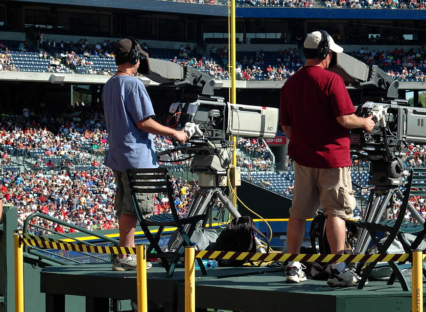 Two TV Camera Operators Broadcasting from Stadium Platform