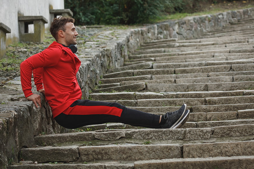 Athletic man resting on stone stairs after outdoor workout