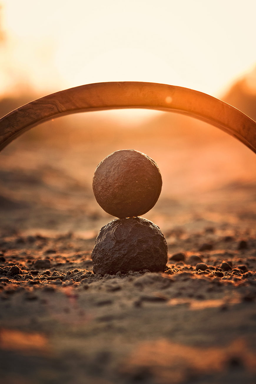 Balanced stones and metal ring at golden hour sunset