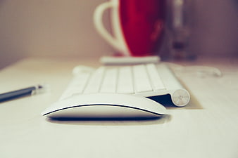 White Wireless Mouse and Keyboard on Desk with Red Mug
