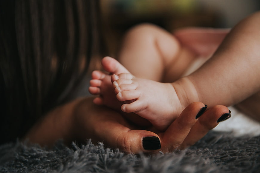 Mother Holding Baby Feet Close Up