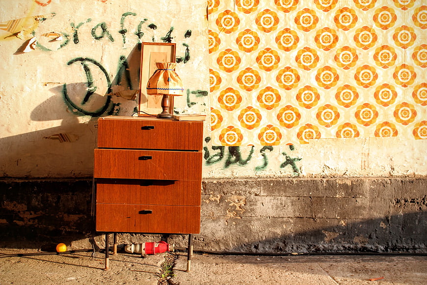 Vintage wooden nightstand with lamp against graffiti wall