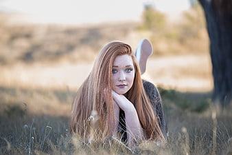 Redhead woman lying in dry grass field portrait
