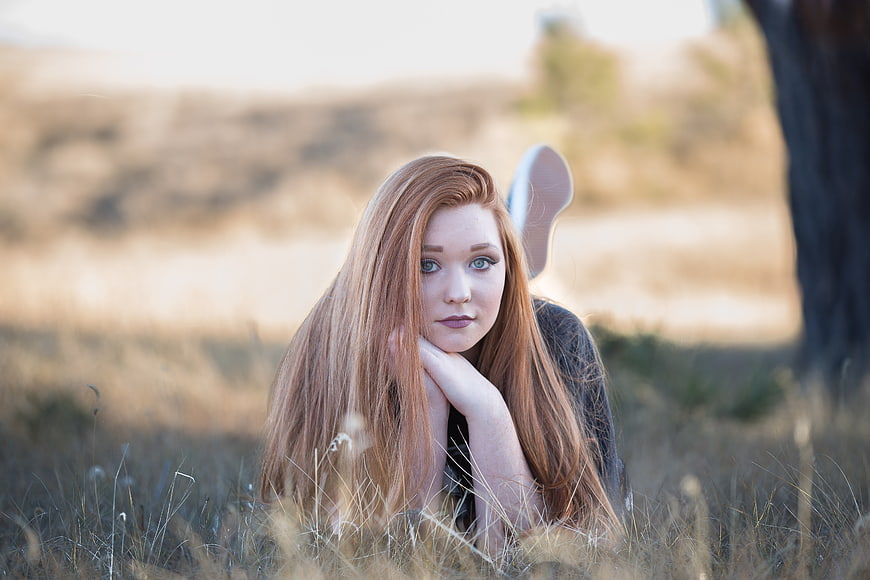 Redhead woman lying in dry grass field portrait