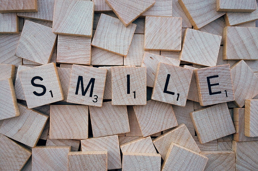 Wooden Scrabble Tiles Spelling Smile on Scattered Background