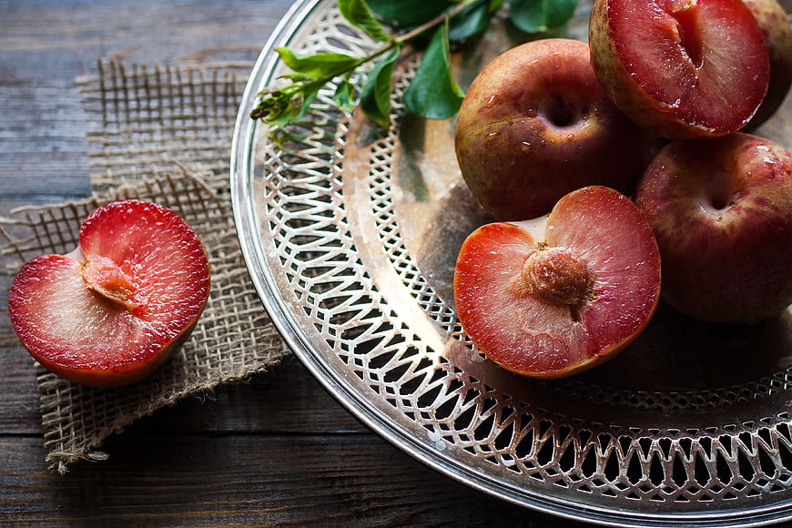 Fresh Red Plums on Silver Platter with Burlap
