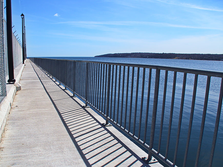 Empty concrete pier with metal railing overlooking blue ocean