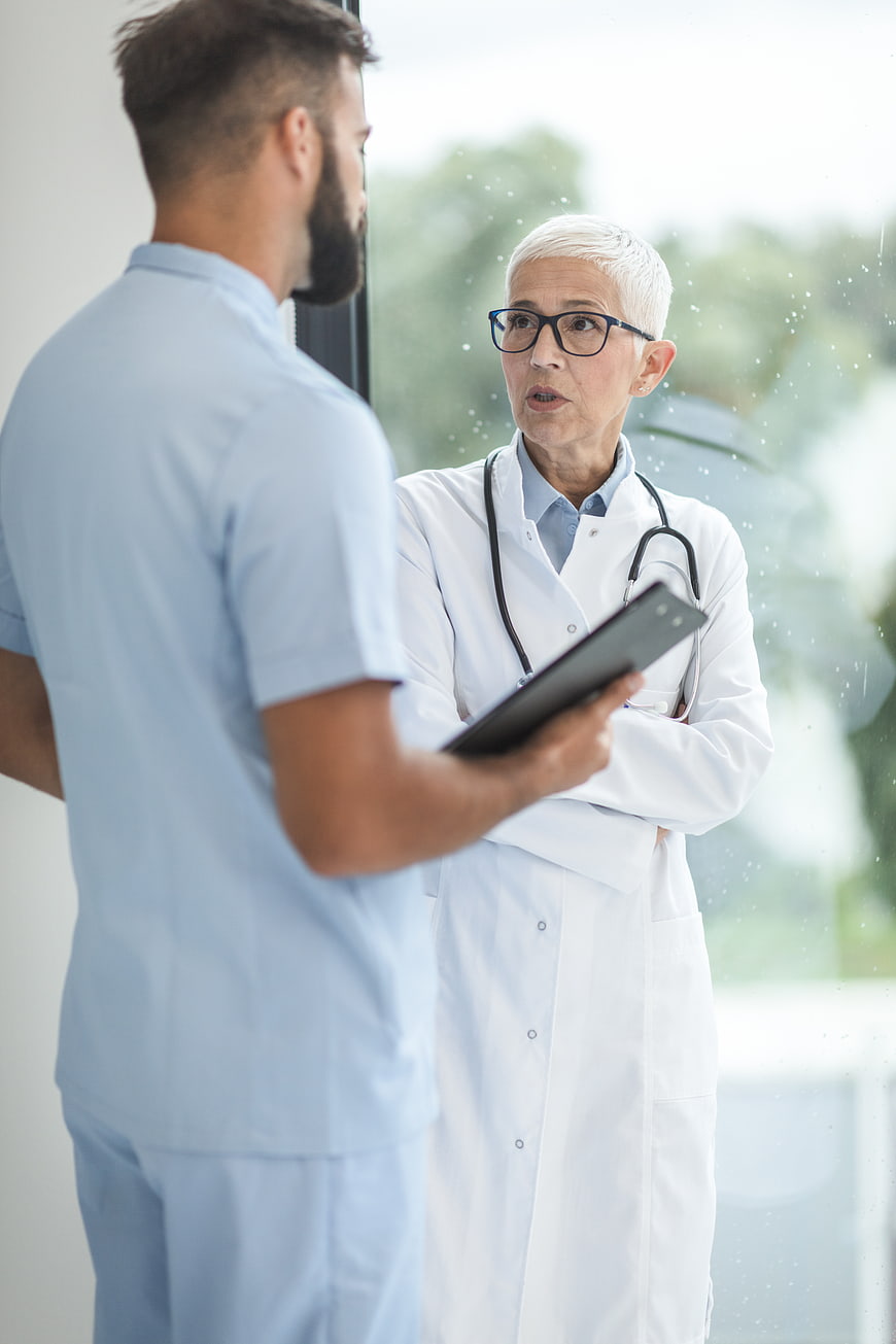 Senior female doctor discussing medical records with male nurse