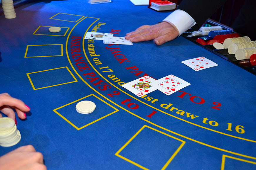 Blackjack game on blue felt table with dealer and chips