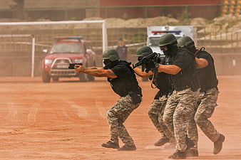 Armed police tactical team training exercise on dirt field